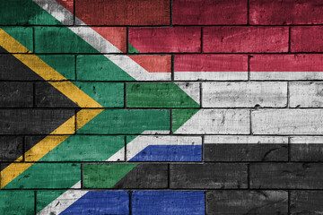 colourful painted big flag of south africa and flag of sudan on a massive old brick wall...