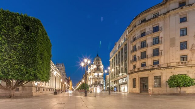 Avenida de la Constitucion day to night timelapse in Seville, Spain. Historic architecture with modern streetlights, pedestrians and urban atmosphere. Iconic Adriatica building glowing after sunset.