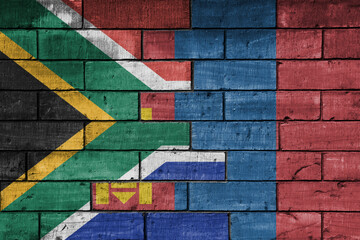 colourful painted big flag of south africa and flag of mongolia on a massive old brick wall...