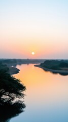 Naklejka premium A river with a sunset in the background. The sun is setting and the sky is a mix of orange and blue. The water is calm and peaceful
