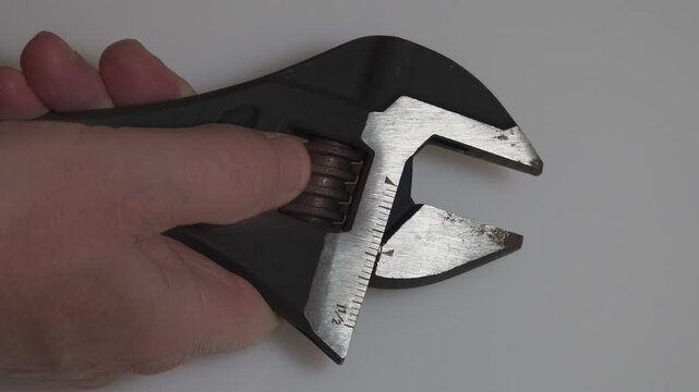 Hand tightening an adjustable wrench on a white background