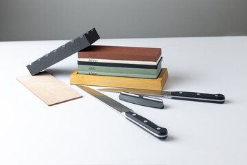 white background on stand lies all the equipment a set for sharpening and polishing kitchen knives...
