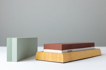 closeup white background on table lies all the equipment a set for sharpening and polishing kitchen knives and various blades different abrasiveness of stones a retainer for knives