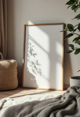 A white framed picture with a brown border is displayed on a wooden floor, accompanied by a woven basket and a potted plant. A4 frame mockup