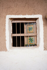 Traditional Saudi mud-house window with hand-painted Najdi patterns and wooden bars, showcasing authentic Arabian architecture and cultural heritage in a classic rural setting of Saudi Arabia.