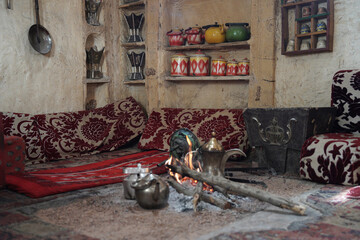 A traditional Saudi Majlis with an open fire, Arabic coffee pots (dallahs), and vintage decor. Showcasing the rich cultural heritage and hospitality of the Arabian Peninsula.

