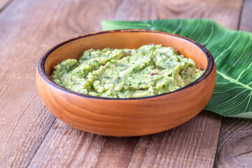 Rustic Guacamole in Wooden Bowl with Fresh Green Leaf