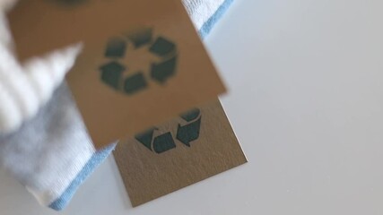 Pile of neatly folded clothes made by recycling material with tag on table top view closeup. 