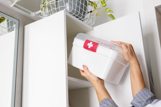 Female hands putting first aid kit with vitamins, drugs, antibiotics and cure at bathroom cupboard.