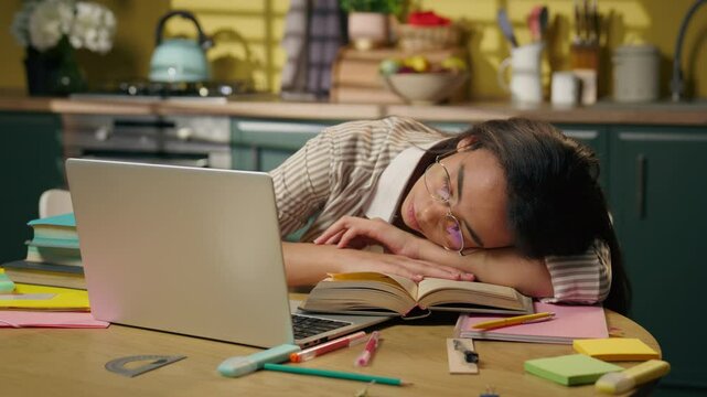 Tired exhausted insomnia Indian Arabian sleeping girl student high school university home education sleep on kitchen table woman female pupil napping sleep lying books boring studying fatigue homework