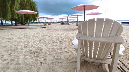 Adirondack chairs with pink umbrellas at the beach in the city