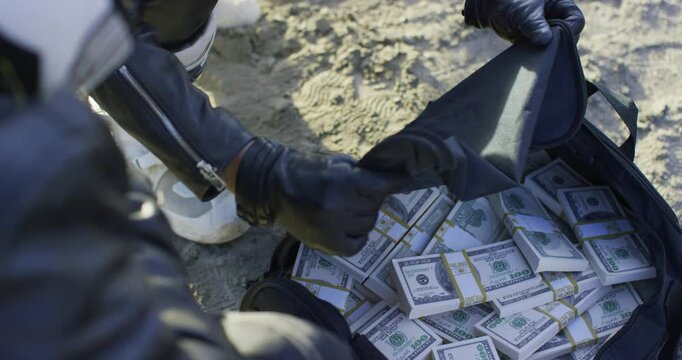 Closeup on bikers checking duffle bag full of cash then closing it up again