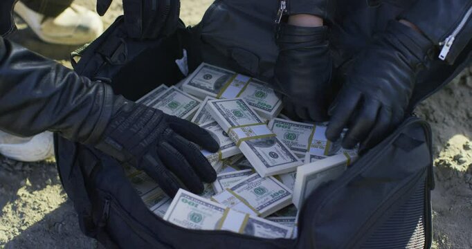 Bikers opening duffle bag filled with tons of cash, close up