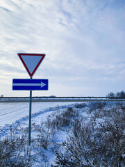 Winter Road Sign - Yield and Directional Arrow in Snowy Landscape