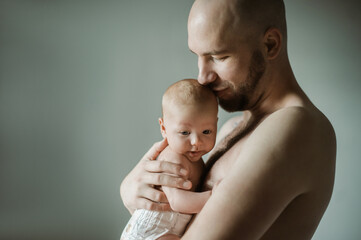 Family, baby and papa with a man hugging his child in studio on a gray background for tender or...