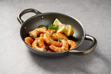 Cooked red prawn with spices in a pan, served with fresh herbs and lemon