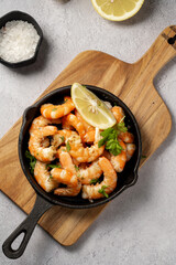 Cooked red prawn with spices in a pan, served with fresh herbs and lemon