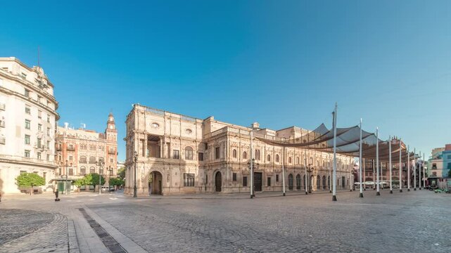 Panorama showing morning timelapse of the Town Hall in Plaza de San Francisco, Seville. Casa Consistorial, Plateresque architecture surrounded by traditional Andalusian buildings under a blue sky