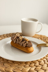 Delicious French artisan hazelnut chocolate coffee cream cheese eclairs on white background with coffee for tasty breakfast