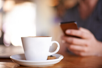 Hand, mobile and person with coffee cup, typing text or writing review for drink closeup. Cafe table, phone or chat notification, communication or influencer post latte on social media profile online