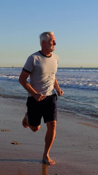 64 year old man getting his exercise at the beach at sunset. Slow Motion. Vertical Video.
