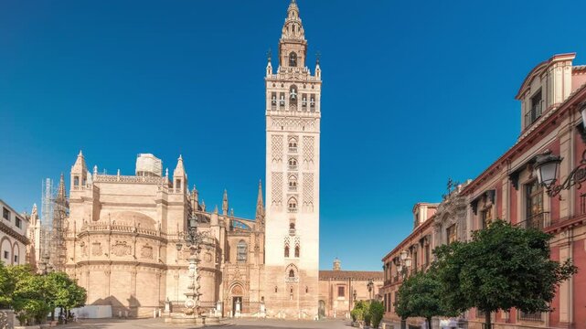 Panorama showing the Seville Cathedral and Giralda Tower timelapse hyperlapse in Seville, Spain. The largest gothic cathedral in the world, located on Virgen de los Reyes square under a blue sky
