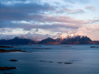 A stunning mountainous landscape features calm, reflective waters and a dramatic, colorful sky