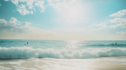 Two individuals enjoying water activities in the ocean under a bright sky with clouds