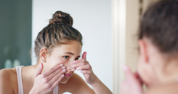 Girl, pimple and skincare in mirror, bathroom and check for zit, acne and morning routine at family home. Teenager, face and dermatology with reflection, cosmetics or insecure for beauty at apartment
