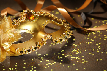Beautiful carnival mask, ribbon and confetti on color background, closeup