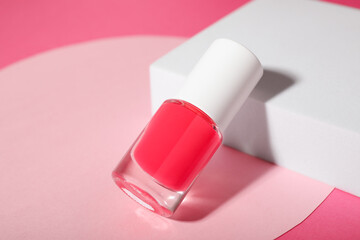 Stylish presentation of nail polish in bottle on pink background, closeup