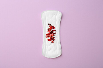 Menstrual pad with sequins on lilac background, top view