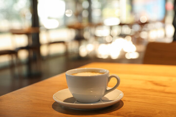 Cup of delicious coffee on wooden table in cafe