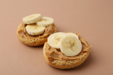 Tasty sandwiches with peanut butter and banana on brown background, closeup