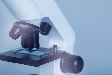 Science. Microscope with glass slide on light grey background, closeup. Space for text