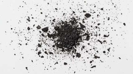 A close-up view of scattered black charcoal powder on a white background, highlighting texture