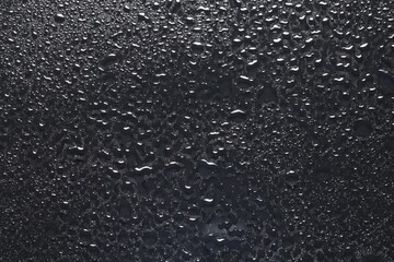 Water drops on dark grey glass surface, top view