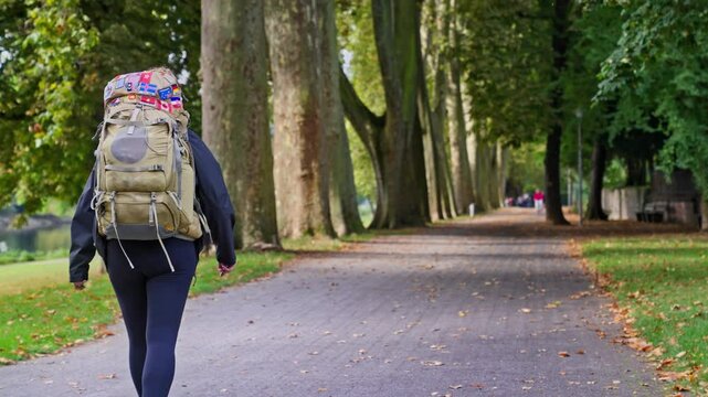 Following behind a backpacking trekker hiking on tree lined park trail in the autumn, Rhine River Valley, Germany