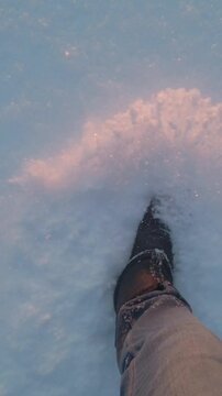 Walking in snow. Legs of man walking on snow in sunlight.