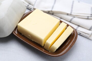 Cut tasty butter in dish on light grey table, closeup