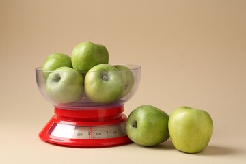 Kitchen scale with apples on beige background. Space for text