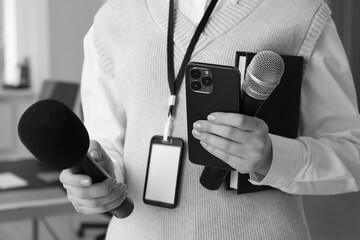 Journalist with microphones, mobile phone and notebook, closeup. Toned in black-and-white