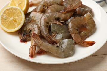 Fresh raw shrimps with lemon on wooden table, closeup