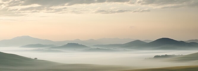 A misty, fog-filled landscape with distant hills and a soft pastel sky at dawn