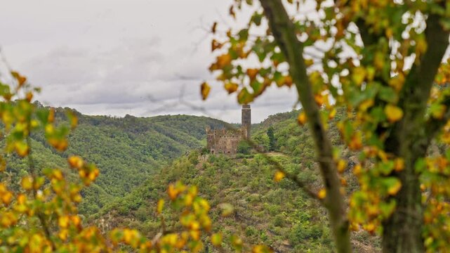 Medieval European Castle on top of a hill seen through fall foliage on a cloudy day with movement, Rhine River Valley, Germany