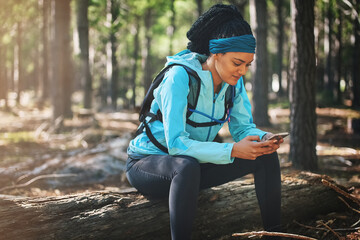 Woman, phone and athlete online in forest, outdoor exercise and research for marathon training. Break, woods and female person in nature for workout guide, sports and typing message on social media