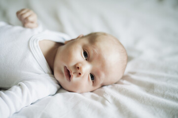 Baby closeup, kid portrait and young newborn on a home bedroom in the morning calm and relax. Relaxing, child face and a house with a toddler ready for a nap, sleeping and rest on a blanket and duvet