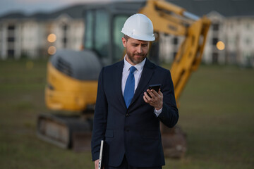 Civil engineer worker at a construction site. Engineer man in front of house background. Confident engineer worker at modern home building construction. Hispanic civil engineer in helmet.
