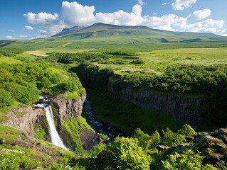 Breathtaking Waterfall Cascading Into A River Surrounded By Lush Green Mountains Under Blue Sky