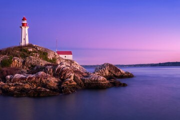 Obraz premium Lighthouse on rocky cliff at sunset against colorful sky. Lighthouse park. West Vancouver. British Columbia. Canada